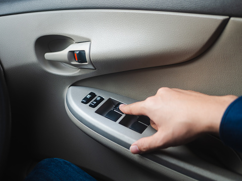 Closeup Driver's hand pressing Car window controls button.