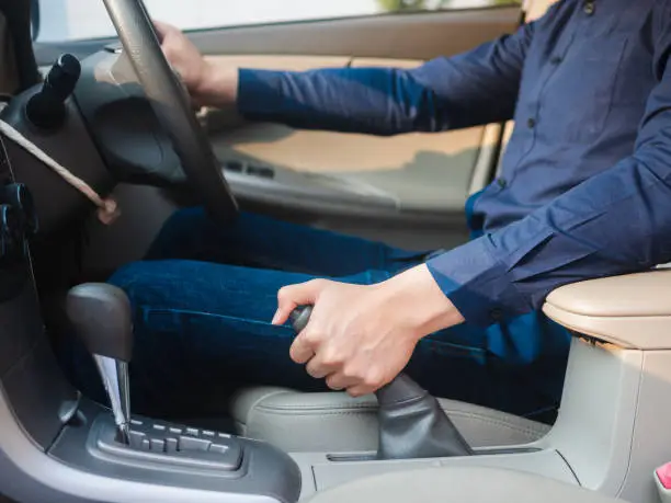 driver's hand pulling the hand brake in a car