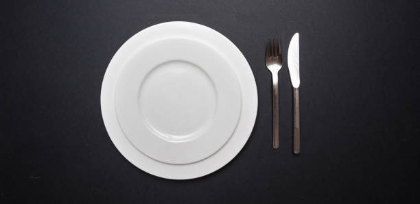 istock Set of empty white plates and cutlery on black color background 1133609886