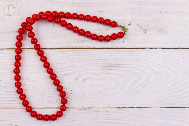 istock Red beads necklace on white wooden background. Top view 1133610955