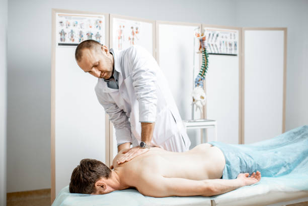 Physiotherapist doing manual treatment Professional senior physiotherapist doing manual treatment to a men's thoracic spine in the cabinet of rehabilitation clinic image manipulation stock pictures, royalty-free photos & images