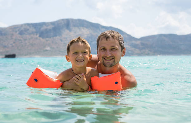 Happy family. Young beautiful father and his smiling son baby boy having fun on the beach of the sea, ocean. Positive human emotions, feelings, joy, kissing.Funny cute child making summer vacations. Balos Lagoon. una familia feliz. joven hermoso padre y su hijo sonriente niño divirtiéndose en la playa del mar, el océano. emociones humanas positivas, sentimientos, alegría, besos. divertido niño lindo haciendo vacaciones de verano. laguna de balos.