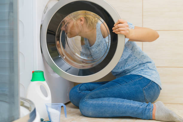 istock Woman looking inside of washing machine 1133620247