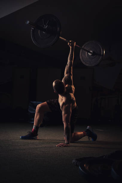 istock Tattooed athlete holding weight over head with one arm 1133627621