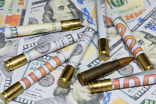 rolled banknotes of dollars inside cartridges over hundred dollar bills money and war concept