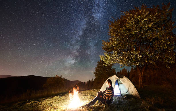 istock Woman resting at camp and tent under under night starry sky 1133634240