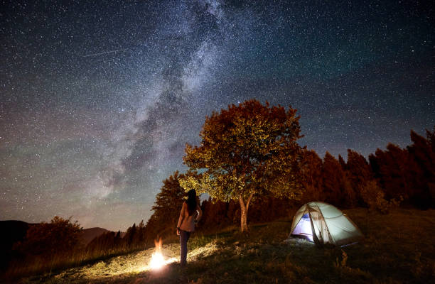 istock Woman resting at camp and tent under under night starry sky 1133634250