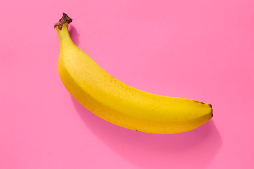 Banana against a bright pink background.