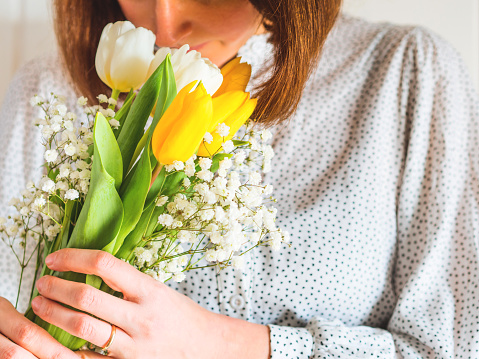 Woman smelling bouquet of tulips. Woman's mother's day. Flowers for Valentine's day. Spring Easter symbol