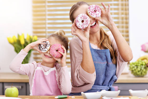 Little girl and her mom in aprons having fun in the kitchen stock photo