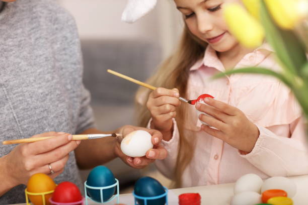 Mother and daughter painting Easter eggs