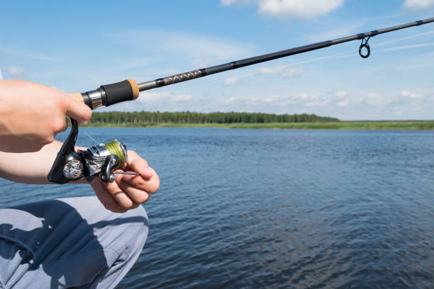 istock hands holding spinning for catching fish against the blue sky and white clouds 1133641694