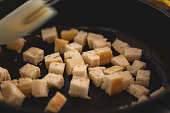 Croutons making, bread pieces dry toasting, close-up