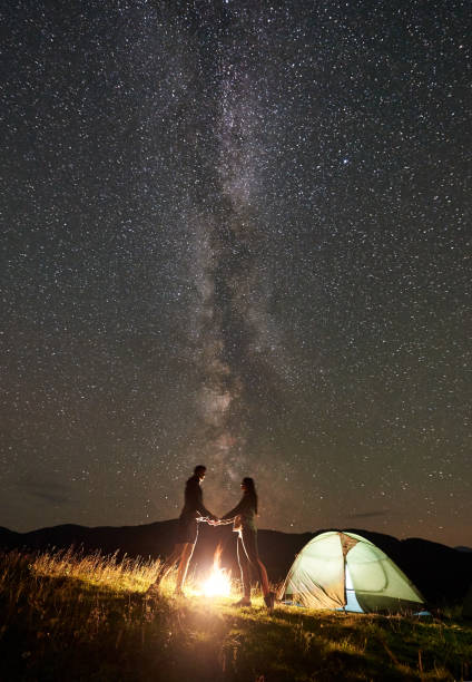 istock Couple tourists at night camp in mountains under starry sky 1133645547