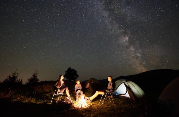 istock Family beside camp, campfire, tent under night starry sky 1133645554