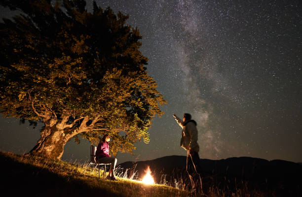 istock Couple tourists at night camp in mountains under starry sky 1133645573