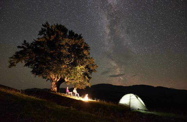 istock Couple tourists at night camp in mountains under starry sky 1133645574