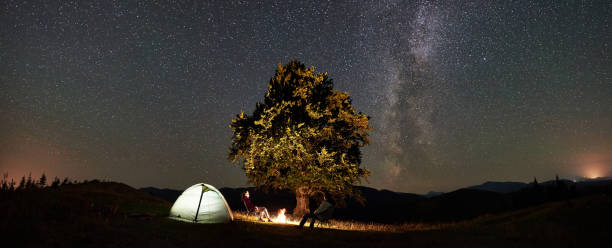 istock Couple tourists at night camp in mountains under starry sky 1133645581