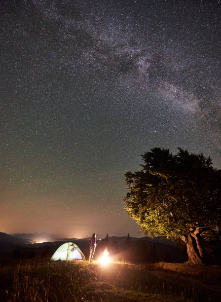 istock Woman resting at night camping in mountains under starry sky 1133645586