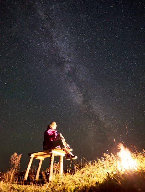 istock Woman resting at night camping in mountains under starry sky 1133645587