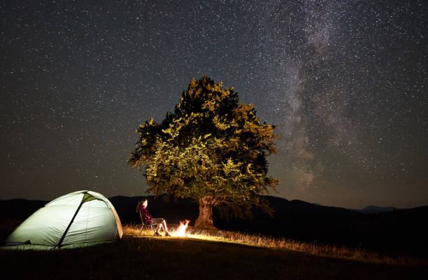 istock Woman resting at night camping in mountains under starry sky 1133645589