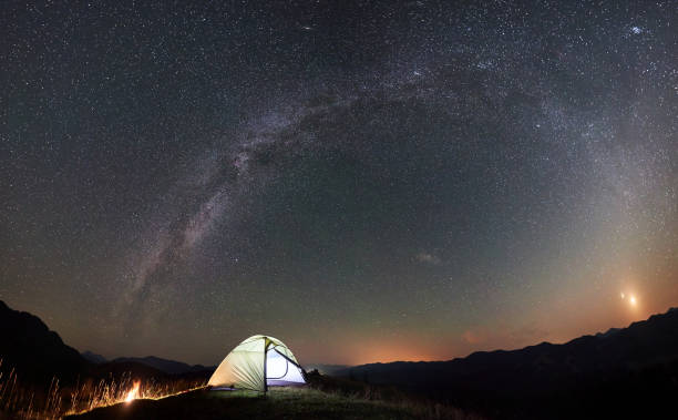 istock Tourist camping at night in the mountains under starry sky 1133645602