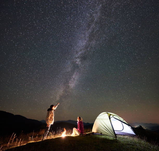 istock Couple tourists at night camp in mountains under starry sky 1133645606
