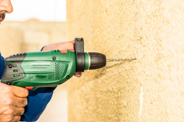 istock a professional mason is making whole into concrete wall by his drill machine 1133646619