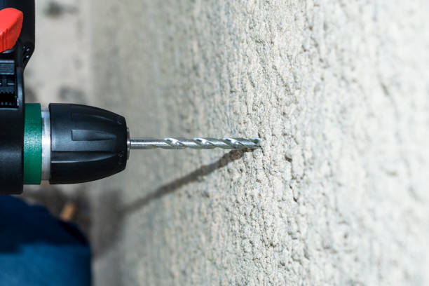 istock a professional mason is making whole into concrete wall by his drill machine 1133646657