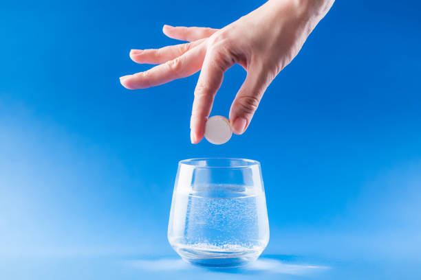 Headache medicine Headache medicine. Woman hand puts aspirin into glass with water. Health care concept with blue background. aspirin photos stock pictures, royalty-free photos & images