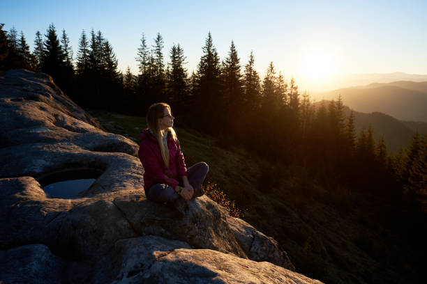 istock Woman hiker sitting on boulder in the mountains at sunset 1133647165