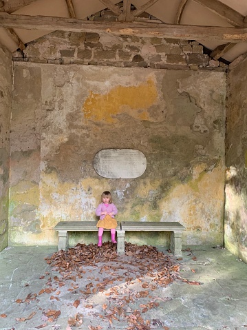 A little girl sits alone in a derelict building with a beautiful background