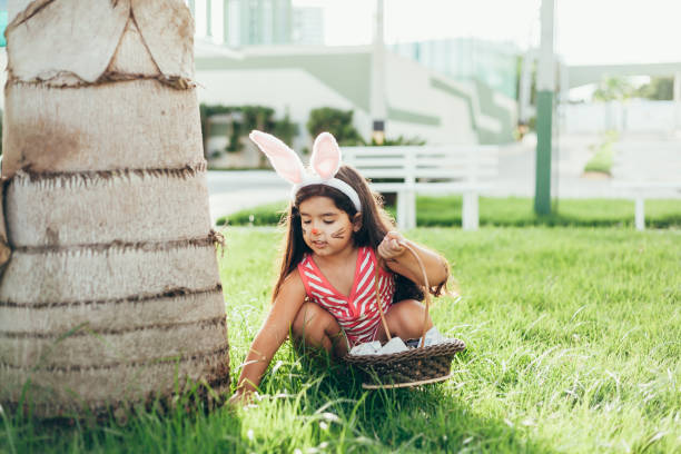 ウサギの耳と庭でイースターエッグのバスケットとかわいい女の子。イースターエッグハント - bunny painting ストックフォトと画像