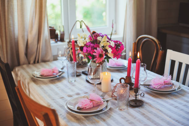 istock Evening dinner at home. Summer festive table setting in beautiful country house. Table decorated with pink flowers and candles. 1133663723