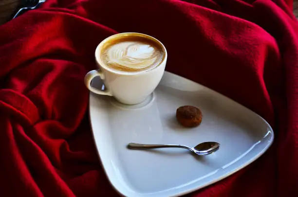 traditional turkish drink salep, in white cup ... next to cinnamon and cookies,red background