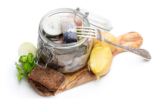 Homemade  marinated herring in glass jar with rye bread and jacket potato isolated on white