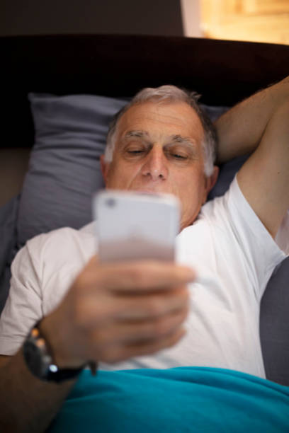 istock Senior man at night in bed texting messages 1133667546