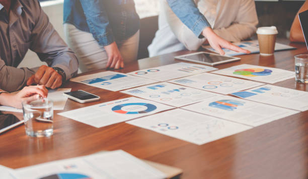 istock Paperwork and hands on a board room table at a business presentation or seminar. 1133668031
