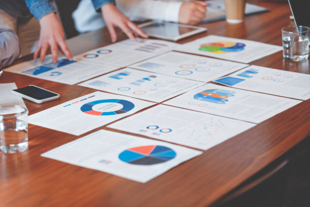 istock Paperwork and hands on a board room table at a business presentation or seminar. 1133668041