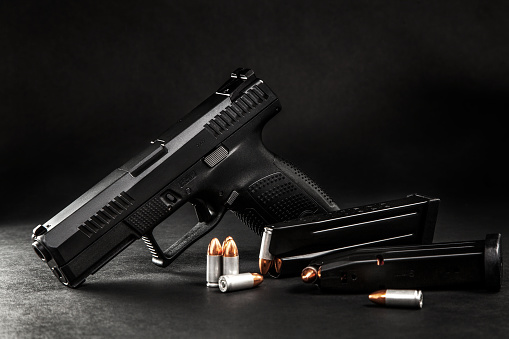 pistola negra y cartuchos en una espalda oscura photo