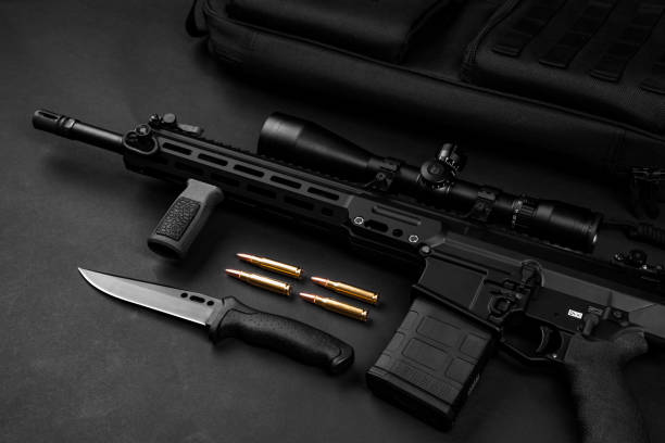 istock modern black automatic rifle with an optical sight lies on a dark background and next to the knife and ammunition 1133668495
