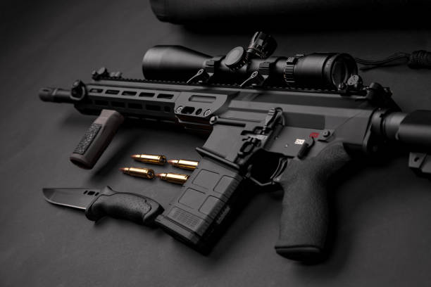 istock modern black automatic rifle with an optical sight lies on a dark background and next to the knife and ammunition 1133668506
