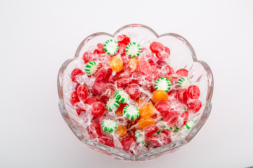A cut glass bowl full of various wrapped candies and mints