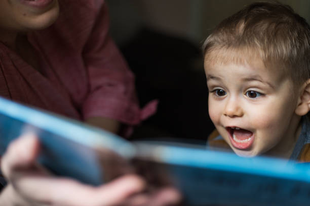 mother teaching son to read book on sofa - picture book imagens e fotografias de stock