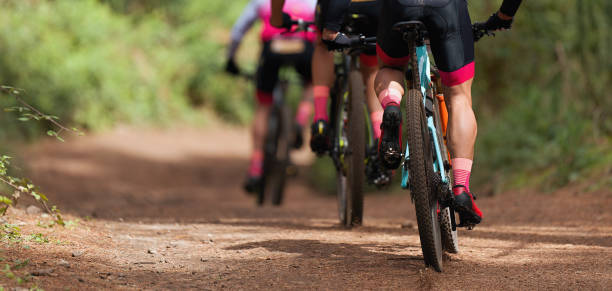 Group of athletes mountain biking on forest trail Group of athletes mountain biking on forest trail, mountain bike race mountain bike photos stock pictures, royalty-free photos & images