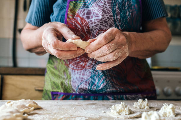 istock Preparing dumplings filled with cottage cheese. Elderly female hands making pierogi or pyrohy, varenyky, vareniki. Traditional Russian cuisine, bakery product, sprinkled flour. 1133685213
