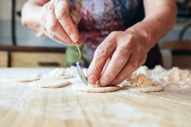 pomarszczone babcie ręce wprowadzenie napełniania ciasta. widok z bliska. - traditional foods zdjęcia i obrazy z banku zdjęć