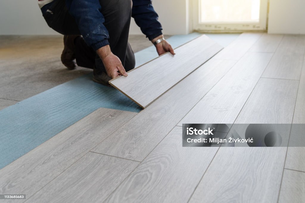 Worker carpenter doing laminate floor work Flooring Stock Photo
