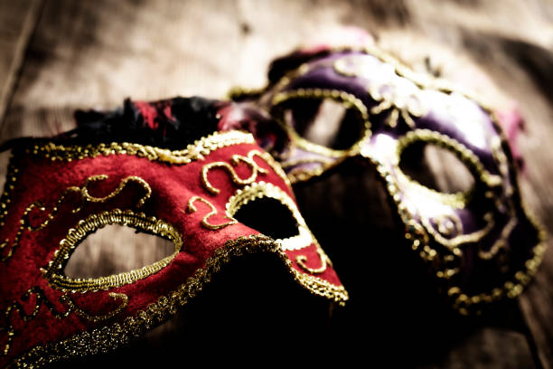 This is a stock photograph of two elegant designed Mardi Gras mask on an old wooden floor. The focus is on the mask in the foreground and falls off quickly in the back.