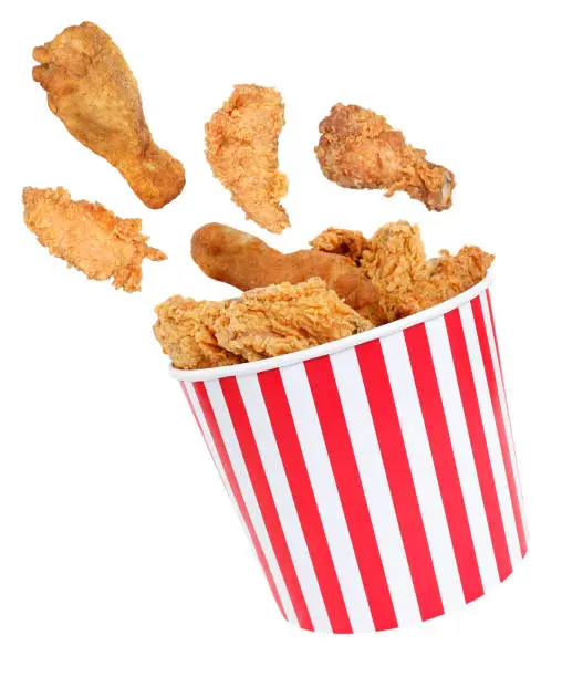 Photo of Perfect fried chicken pieces flying around in red white striped box